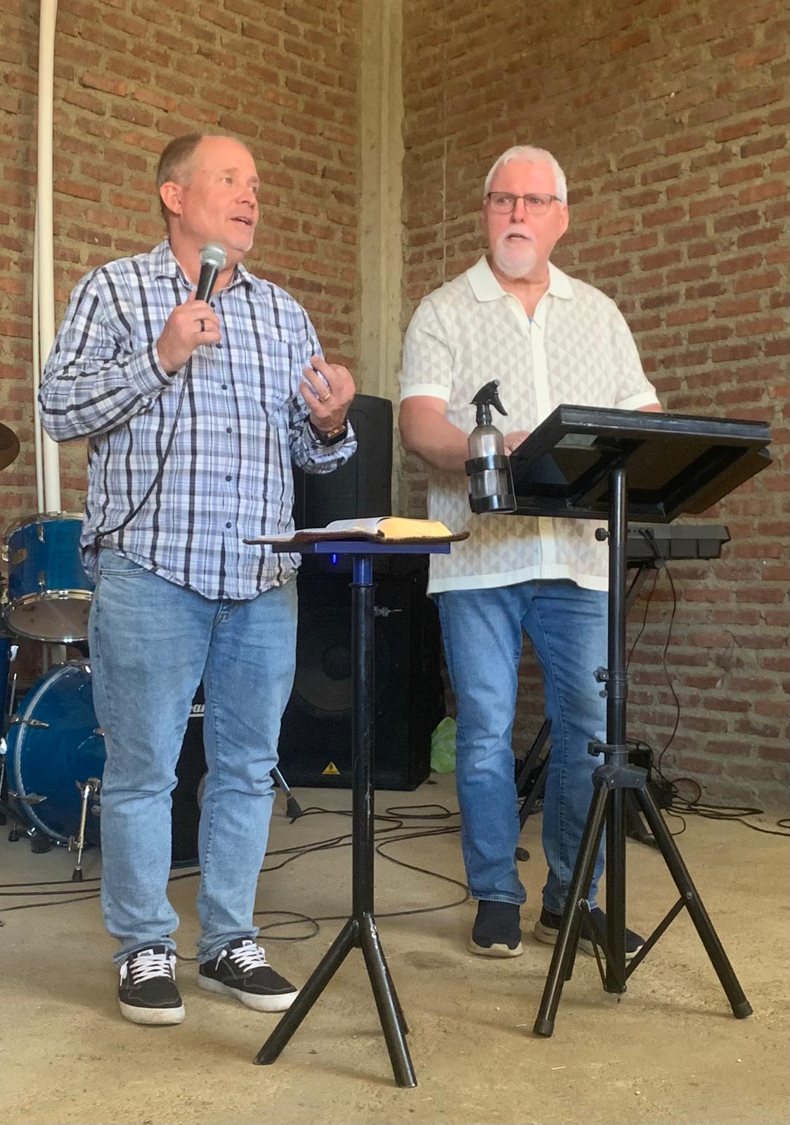 David Larson and another pastor preaching together in a brick venue