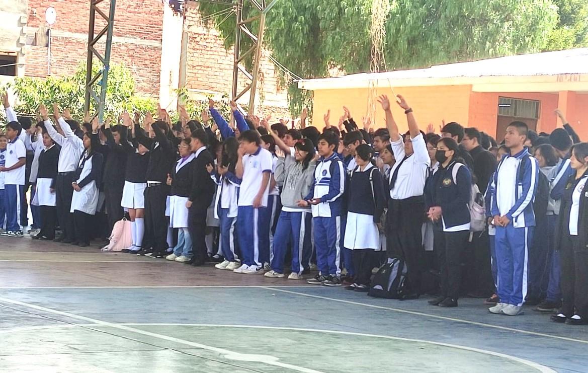 Hundreds of students with hands raised praying the salvation prayer at a school in Bolivia